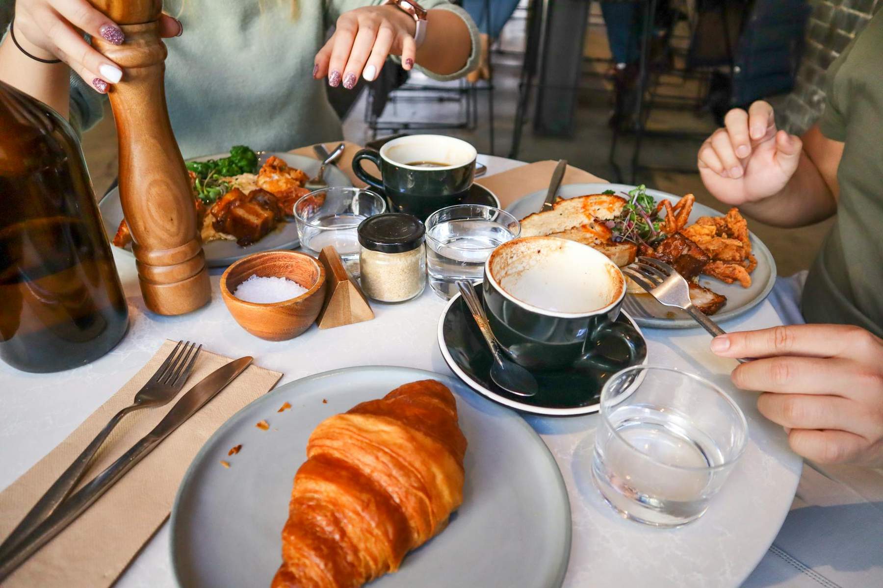 A flat white on a café table beside a brunch plate