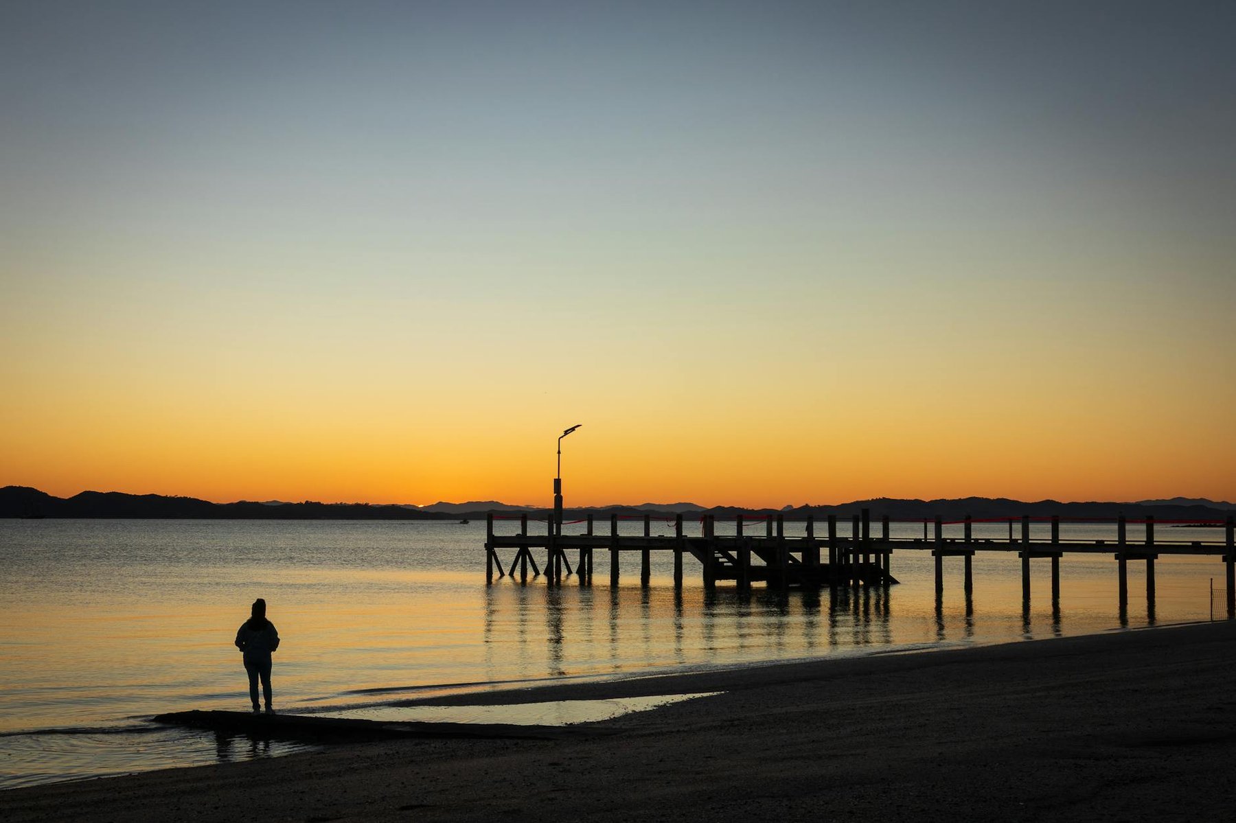 Auckland beach with golden sand and calm water at Mission Bay