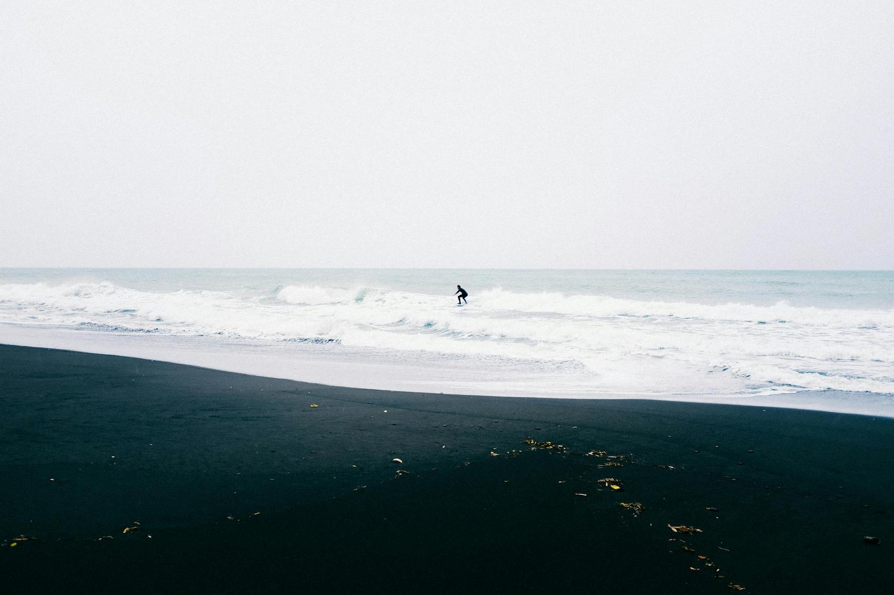 Surfers riding the Tasman Sea waves at Piha Beach