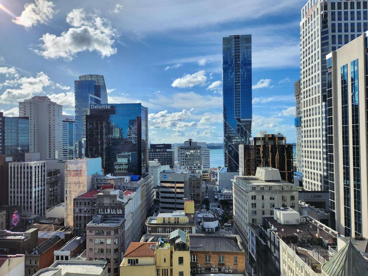 Auckland's city centre from above, with glass office towers and older low-rise buildings running down towards the Waitematā Harbour