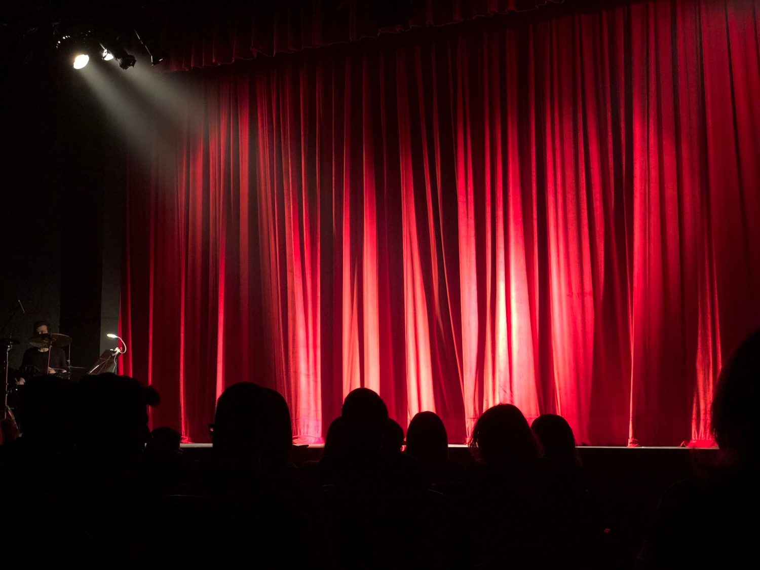 A comedian on stage under a spotlight during a comedy festival show