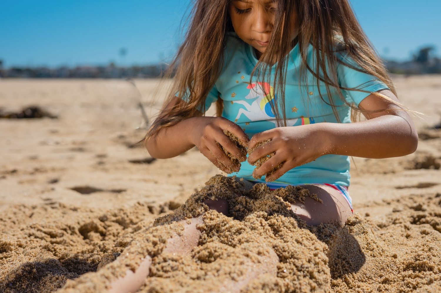 Kids playing on the sand at a calm Auckland harbour beach