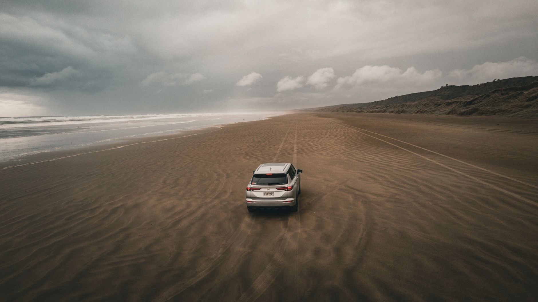 A car on a winding coastal road out of Auckland
