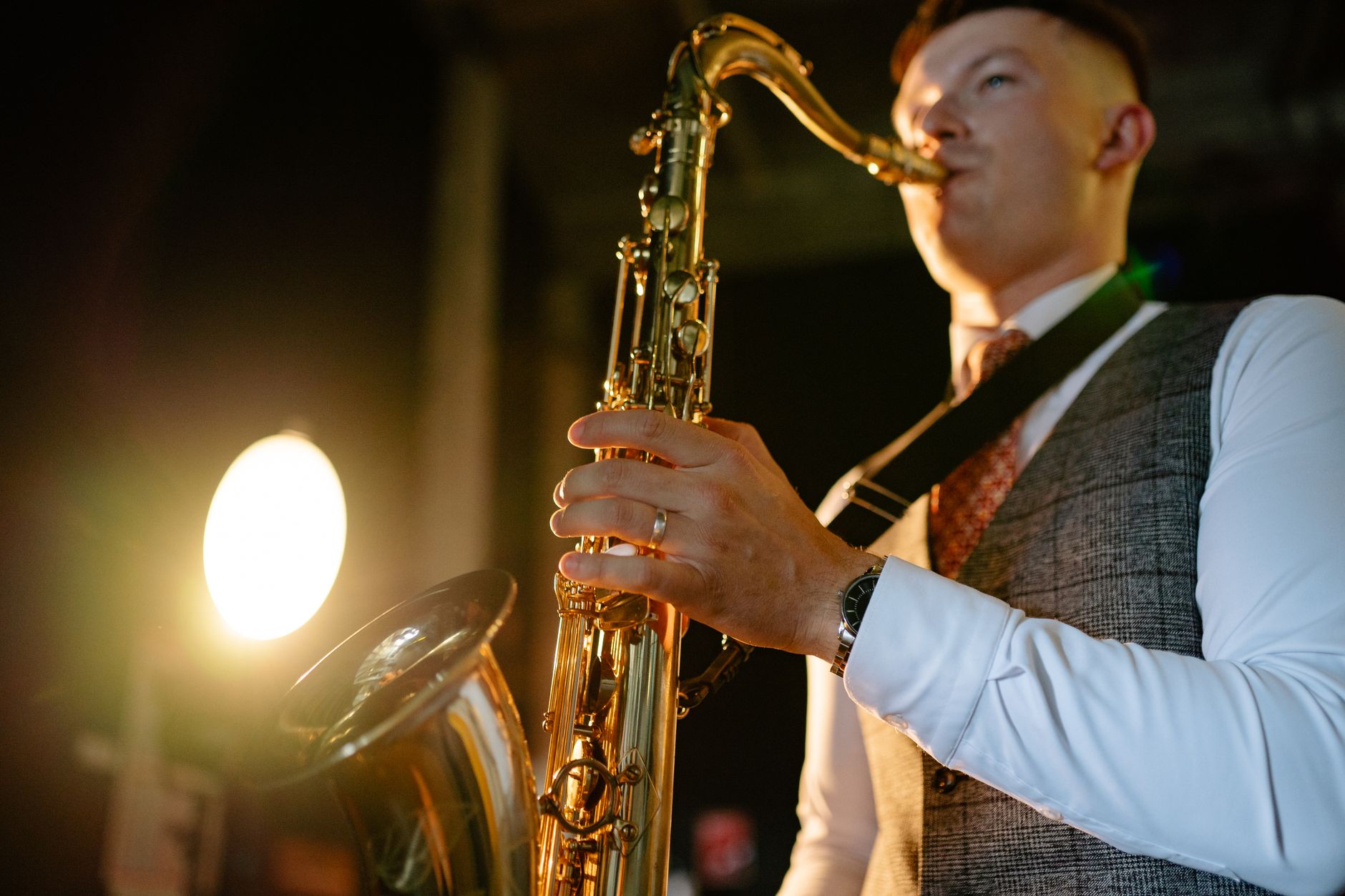 A saxophonist performing under warm stage lights at a jazz night.