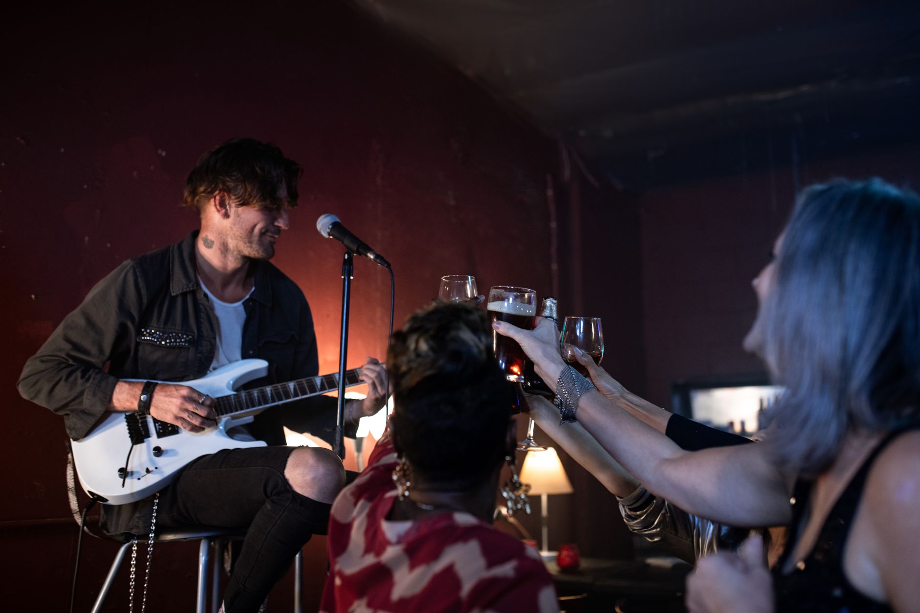 A musician playing guitar to a crowd in a bar.