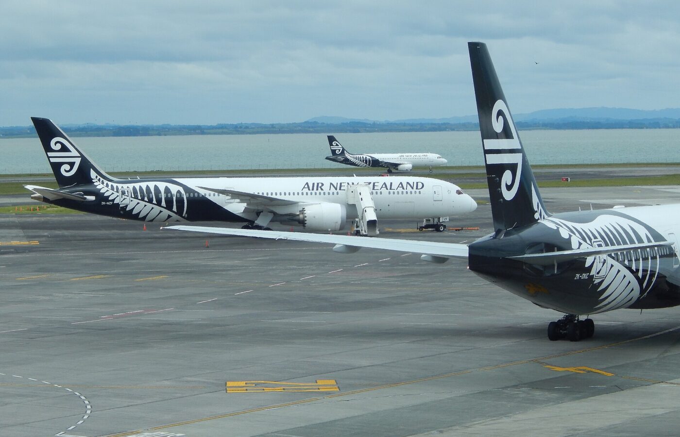 Air New Zealand Boeing 787 and Airbus A320 aircraft on the apron at Auckland Airport with the harbour behind