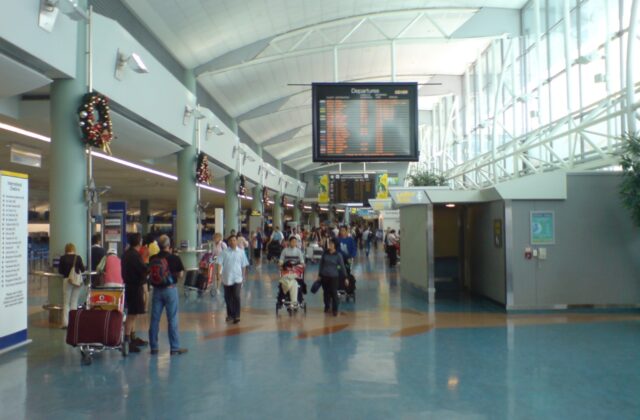 The international check-in hall at Auckland Airport, with departure boards, check-in rows and passengers with luggage trolleys