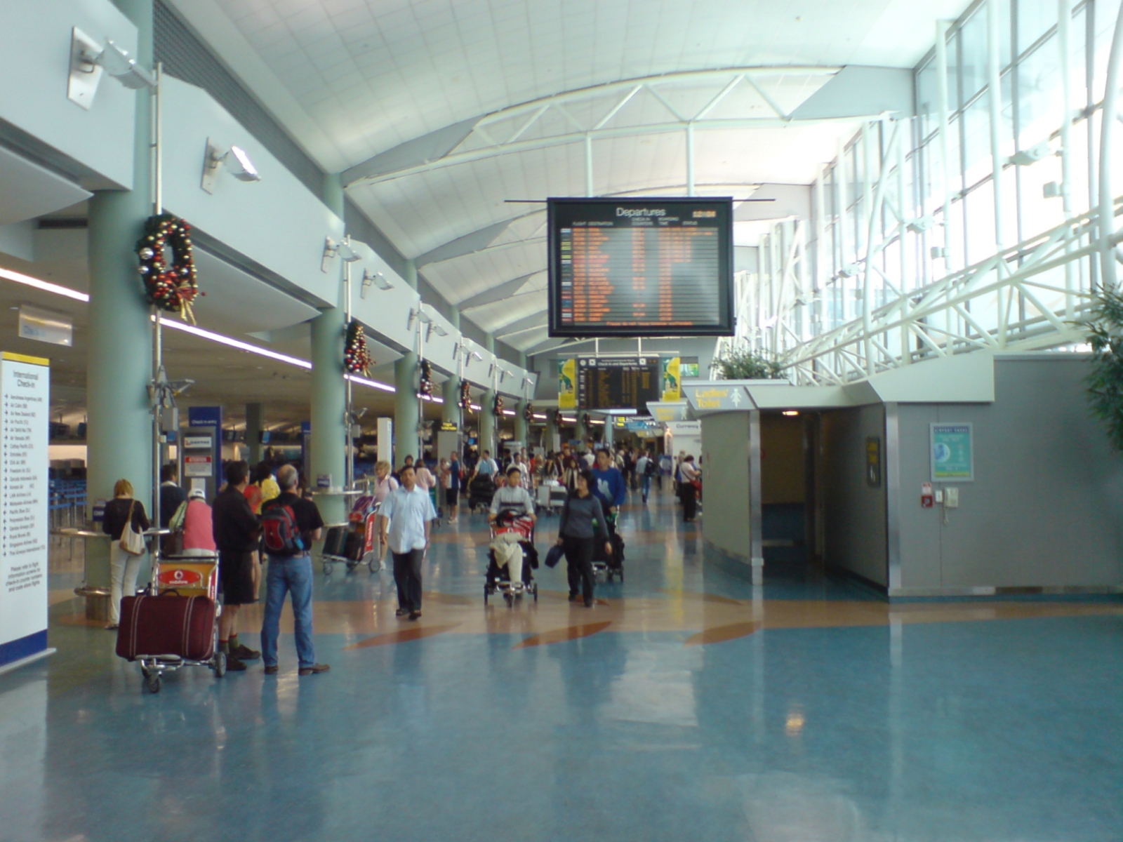 The international check-in hall at Auckland Airport, with departure boards, check-in rows and passengers with luggage trolleys