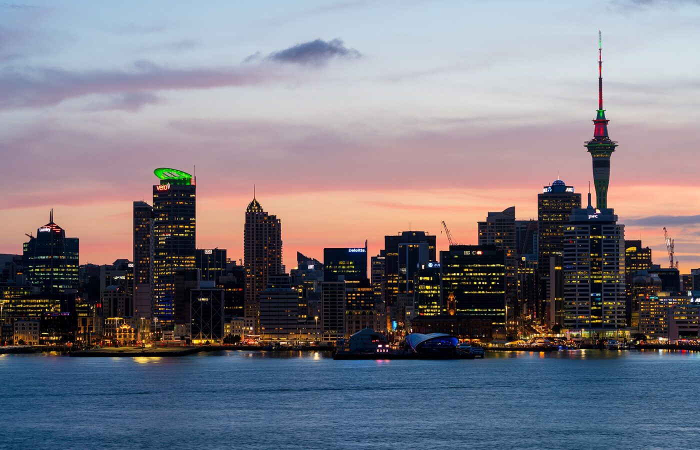 Auckland's city centre skyline at dusk across the Waitemata Harbour with the Sky Tower lit