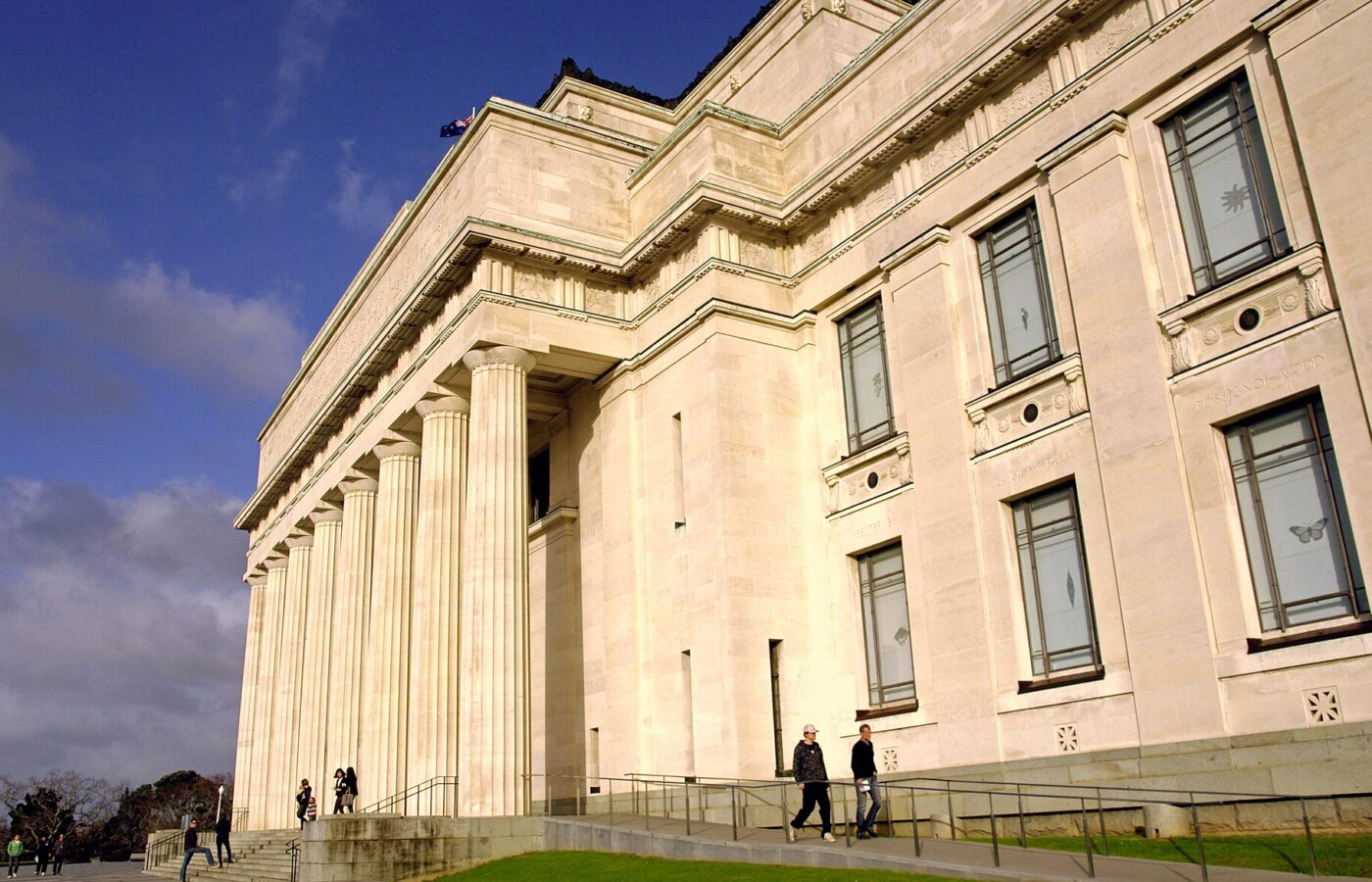 The colonnaded stone facade of the Auckland War Memorial Museum with visitors on the steps