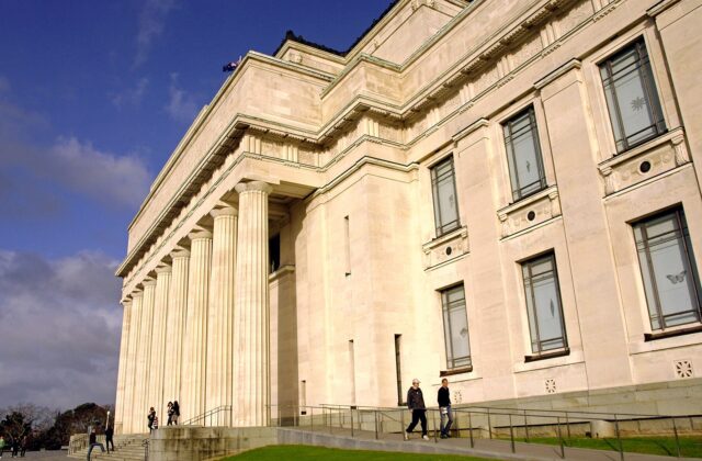 The colonnaded stone facade of the Auckland War Memorial Museum with visitors on the steps