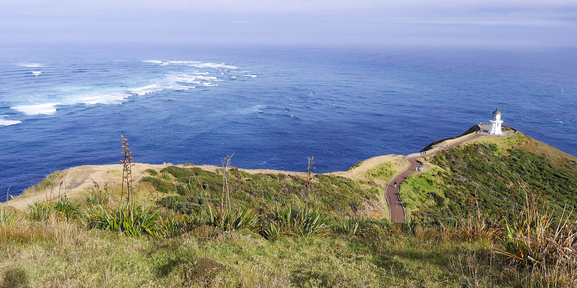 Cape Reinga lighthouse on its headland above the churning line where the Tasman Sea meets the Pacific Ocean