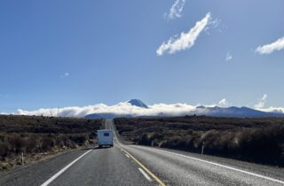 A campervan on the Desert Road through Tongariro National Park, with the volcanoes on the skyline under cloud