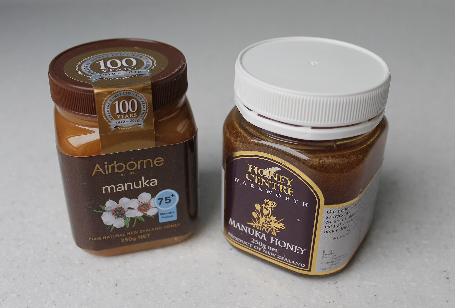 Two jars of New Zealand mānuka honey side by side, both 250 g, one labelled 75+