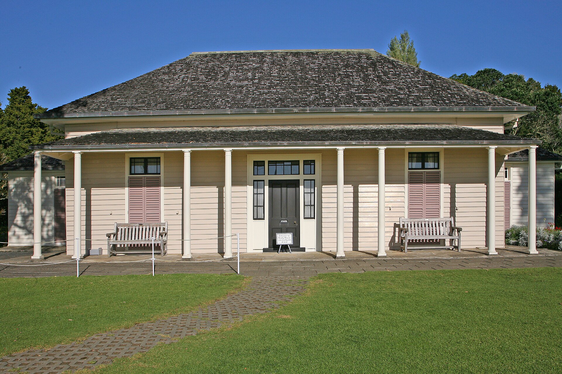The white weatherboard Treaty House at Waitangi, with its veranda and lawn under a blue sky